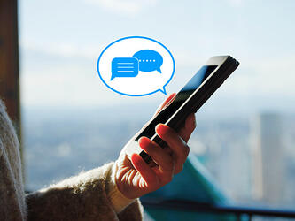 person holding phone, graphic of speech bubble with message icons